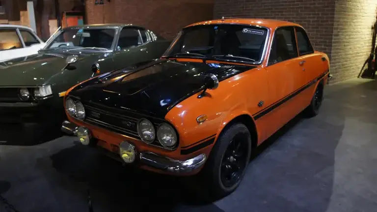 A black and orange Isuzu Bellett GT-R displayed inside the Glion Museum in Osaka, Japan