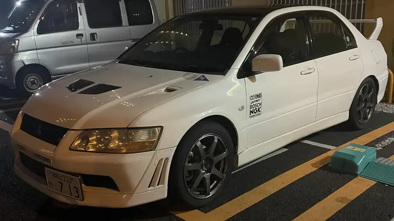 Rented white Mitsubishi Lancer Evolution 7 in a coin parking at night in Osaka, Japan