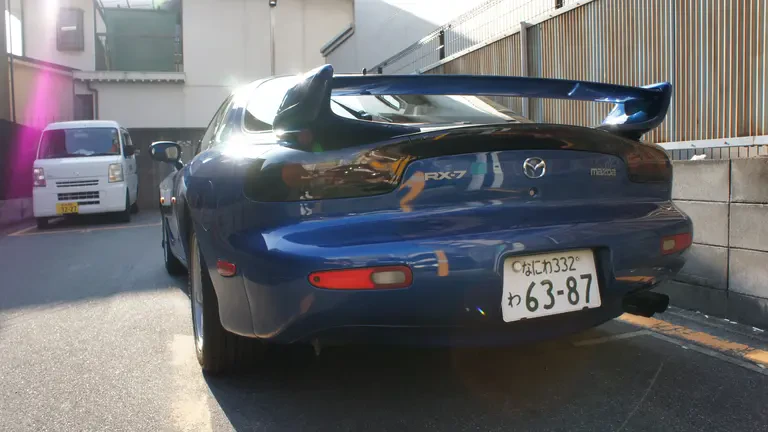 Back view of a rented blue Mazda RX-7 in a coin parking in Nara, Japan