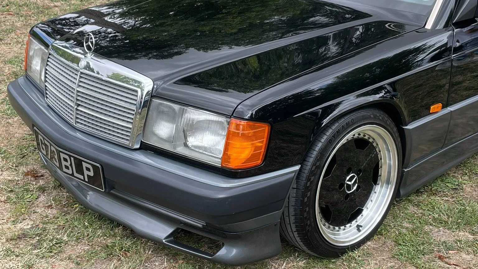 Side view of the front-end of a stanced black Mercedes-Benz 190E