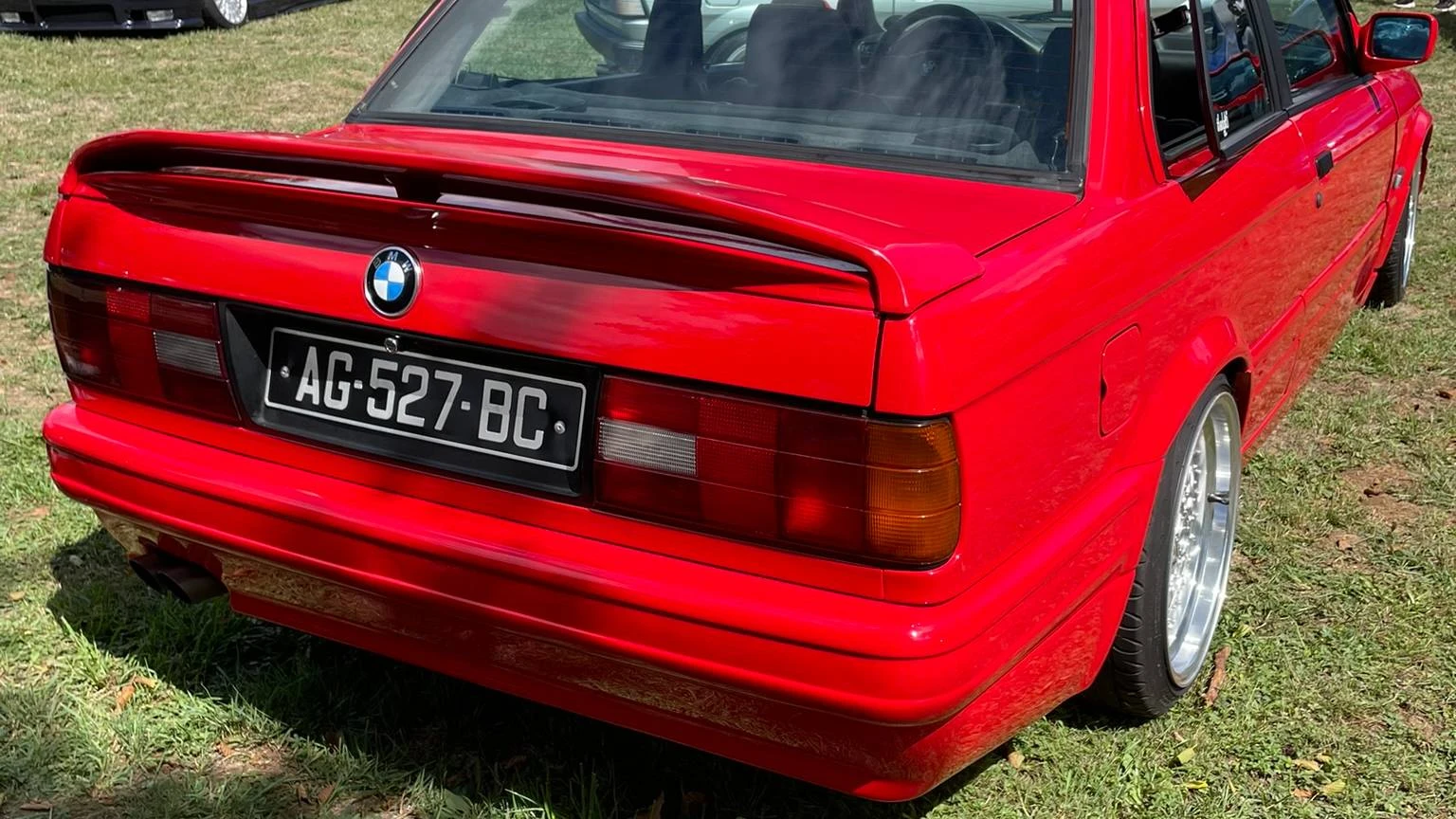 Rear side view of a stanced red 1990 BMW 316i