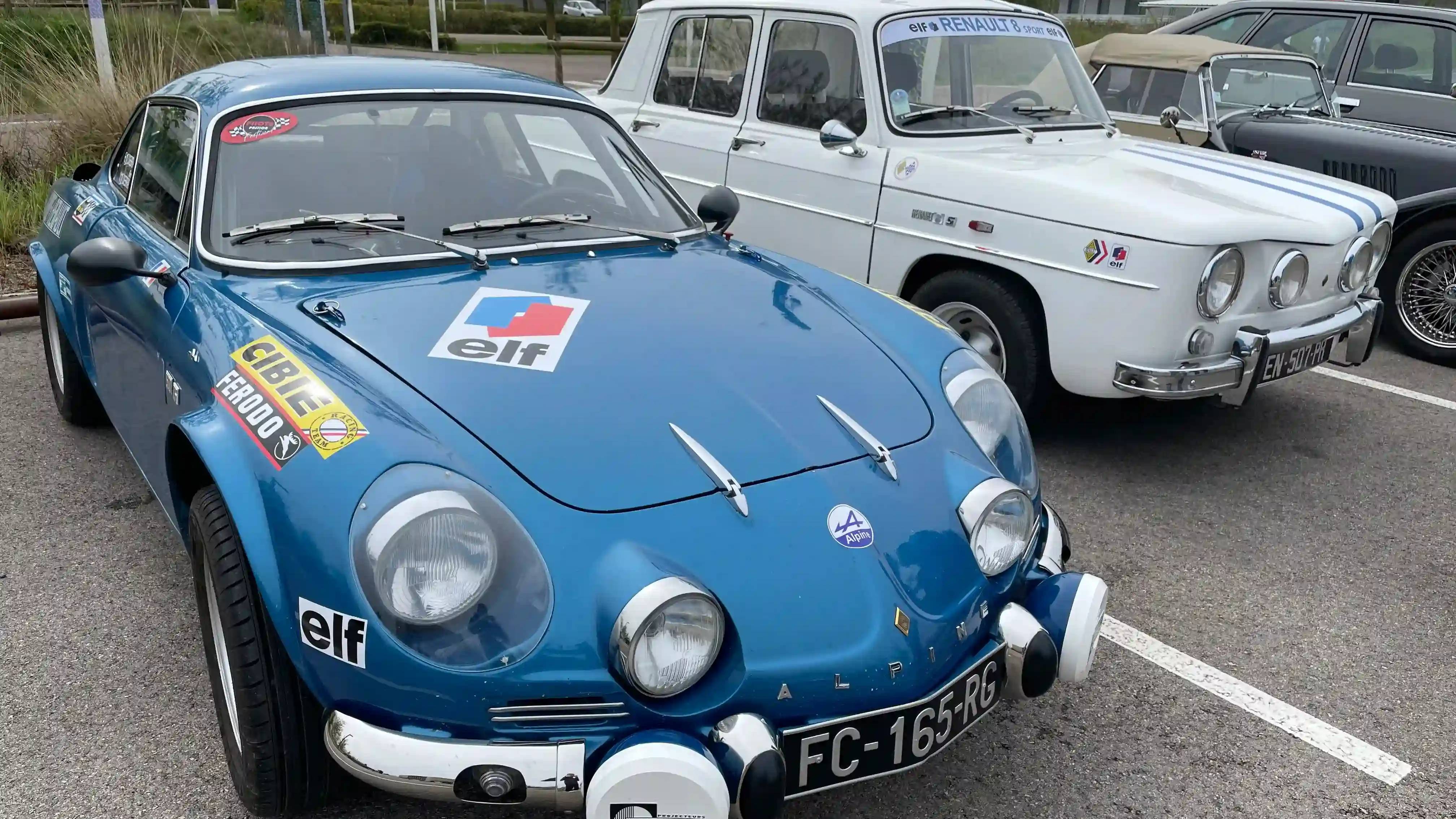 A blue Alpine A110 next to a white Renault 8, both parked