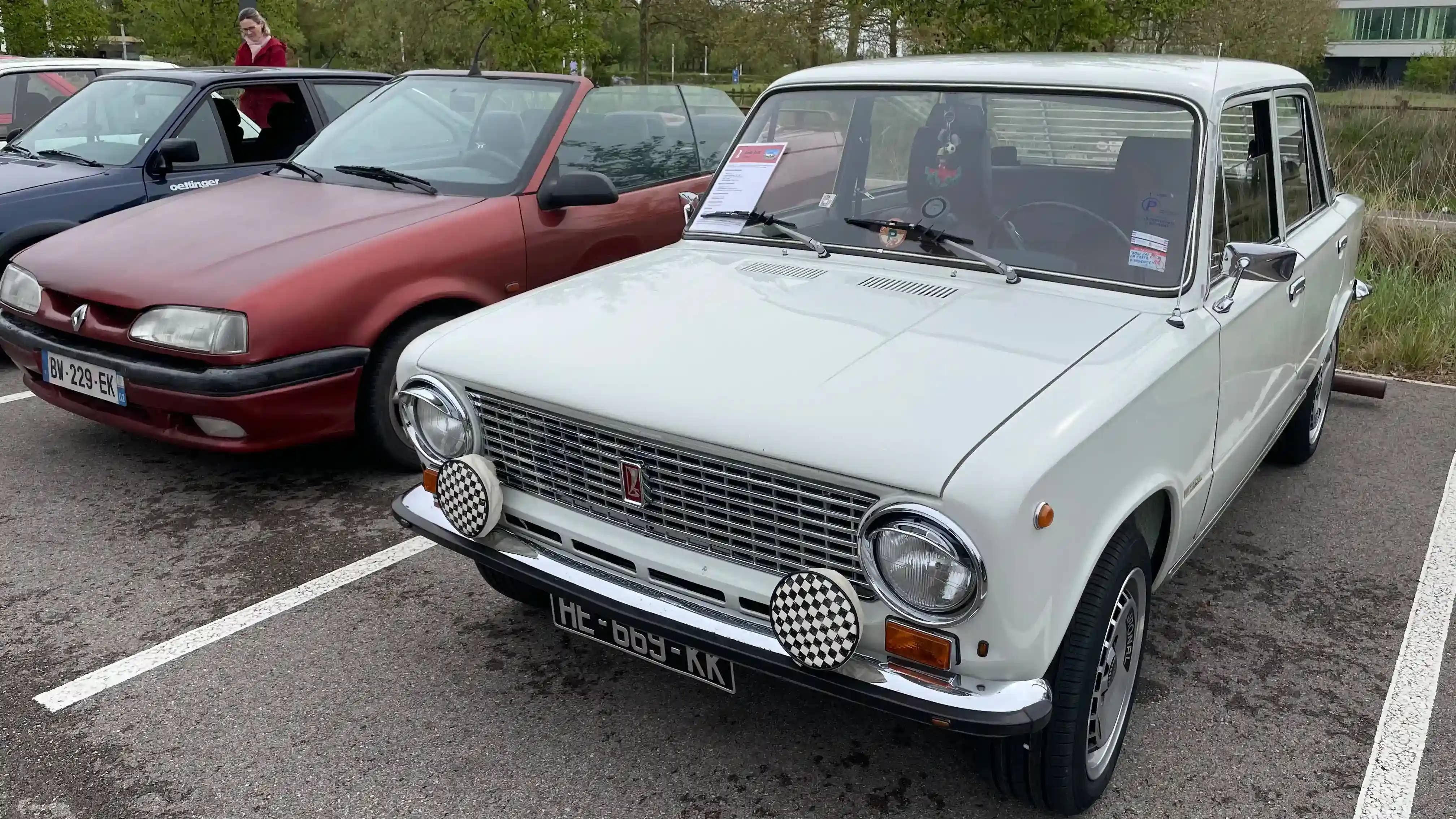 A parked white Lada Zhiguli next to a brown convertible Renault 19