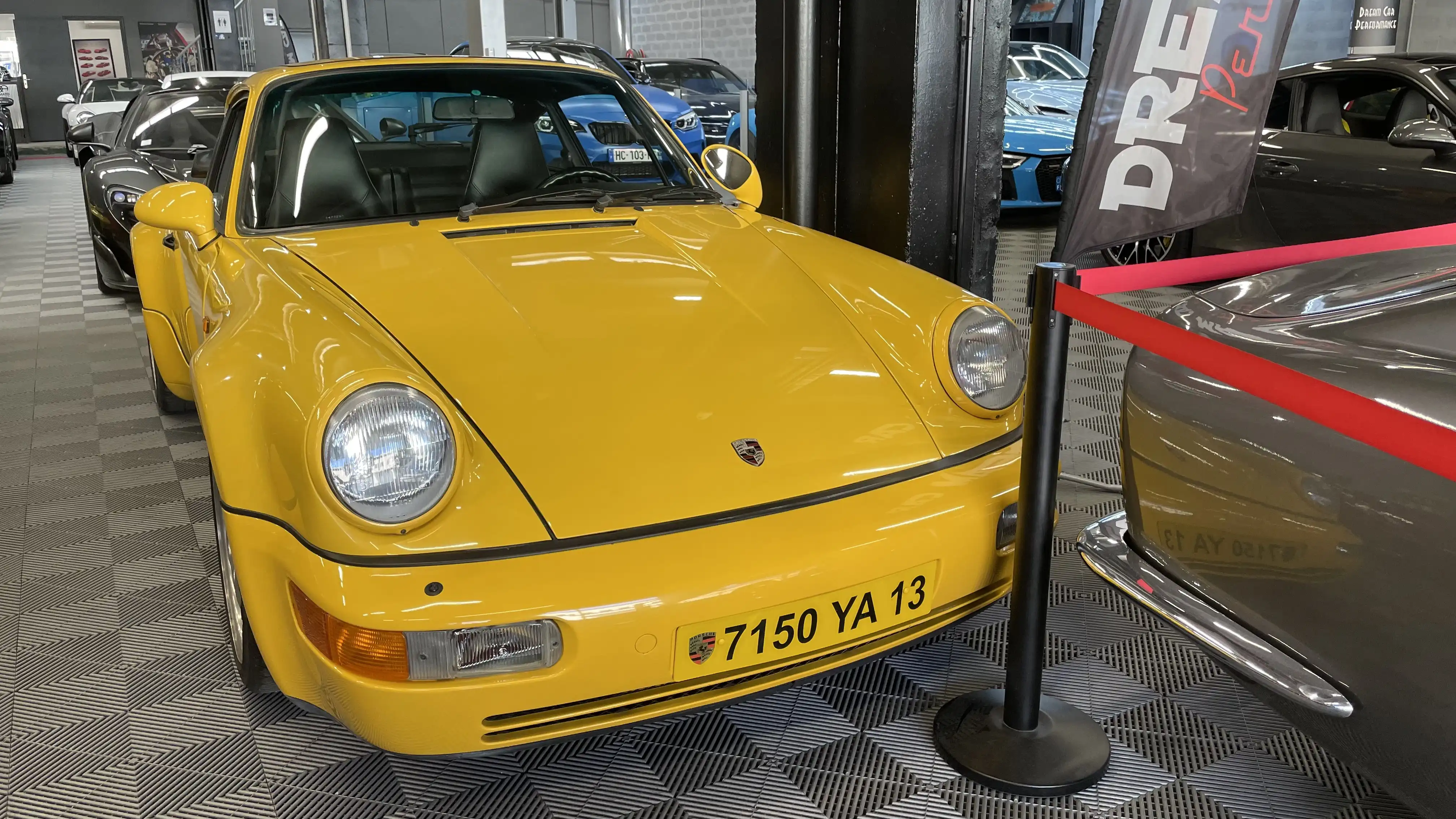 Front view of a yellow Porsche 964 turbo inside the showroom of Dream Car Performance