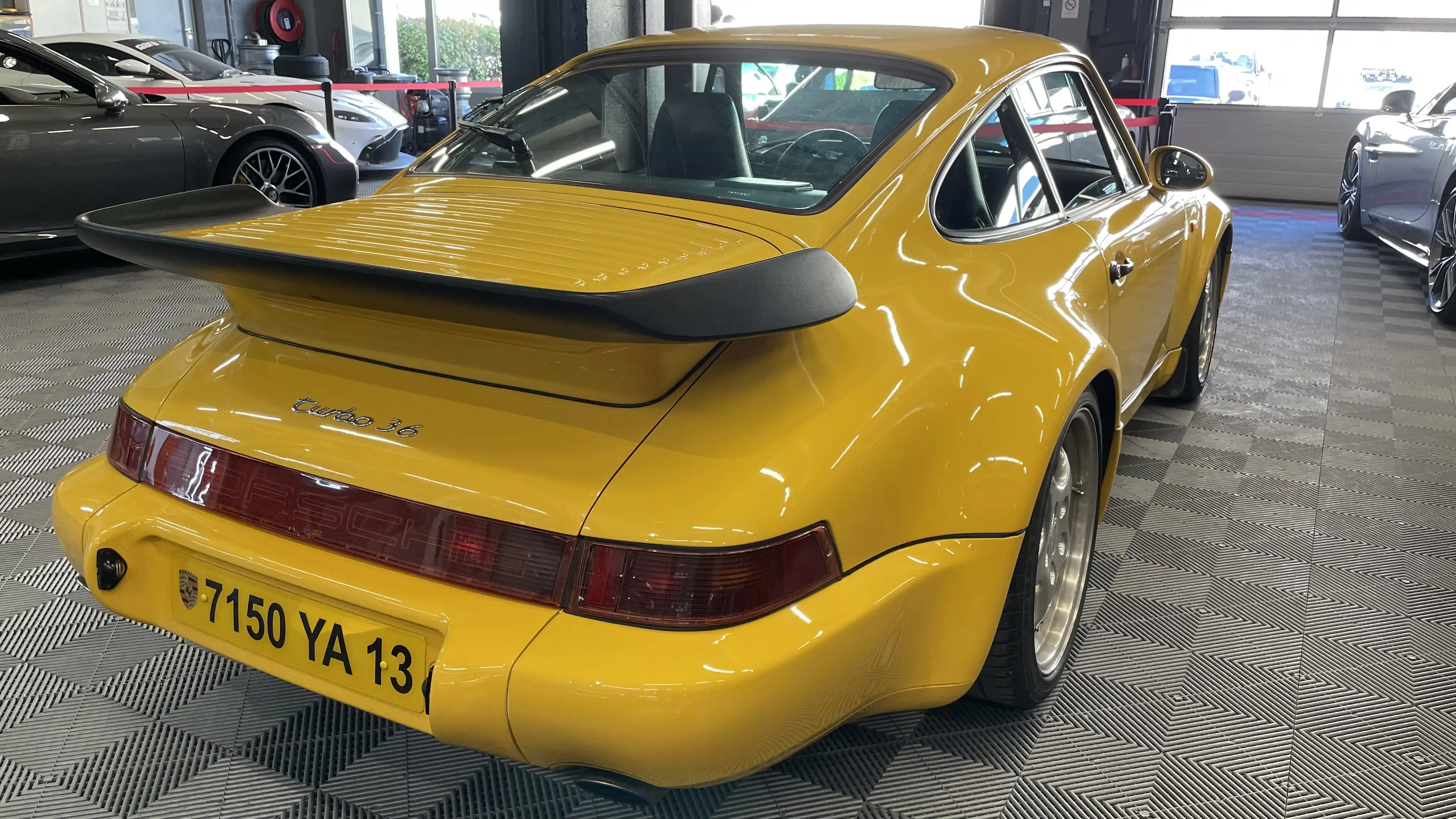 Rear view of a yellow Porsche 964 turbo inside the showroom of Dream Car Performance