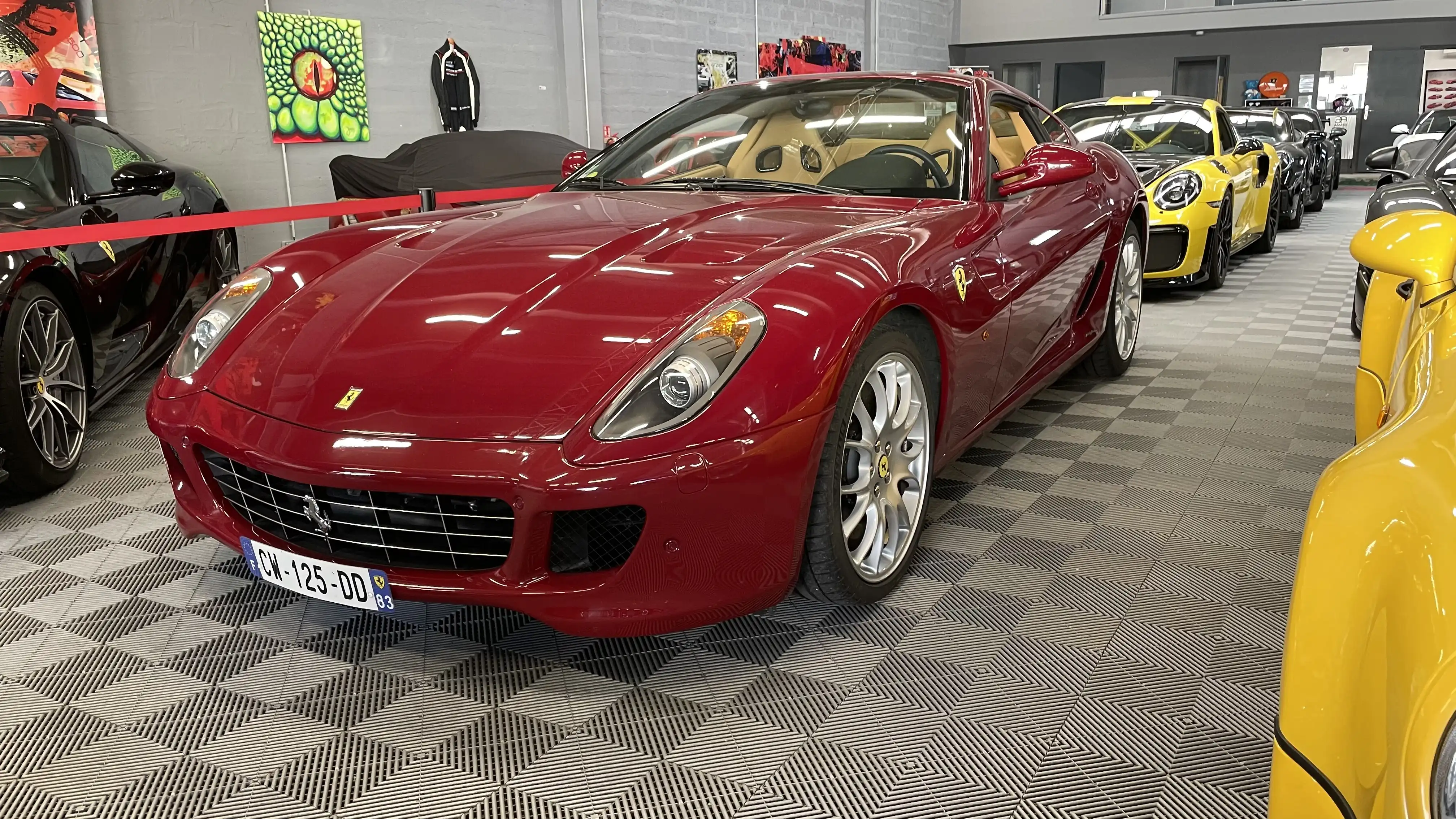 A red Ferrari 599 in front of various luxury cars inside the showroom of Dream Car Performance
